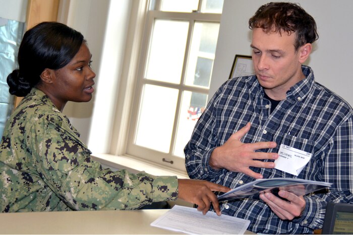 A sailor talks to a person holding papers.