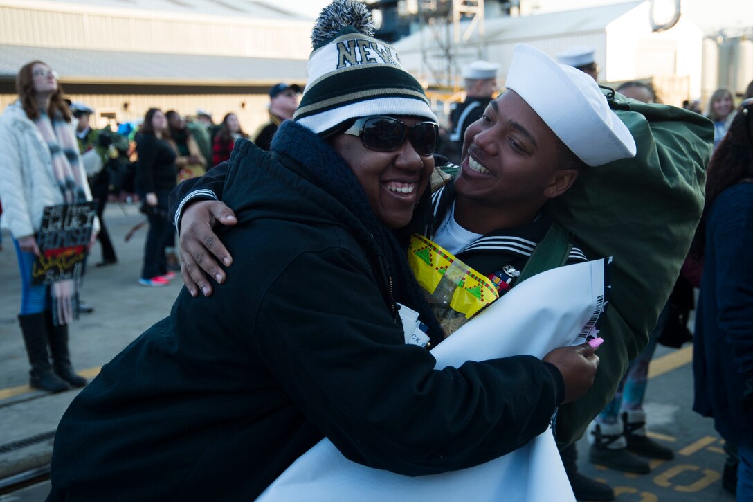 A sailor and a person hug.