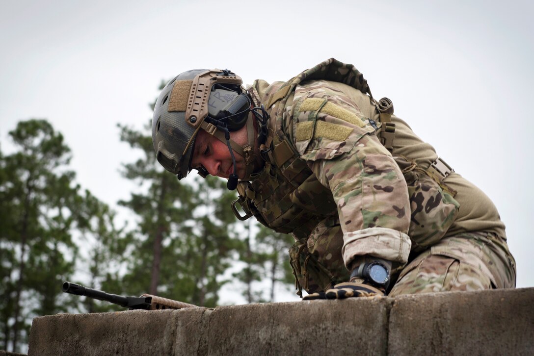 An airman climbs over a wall during combat survival training.