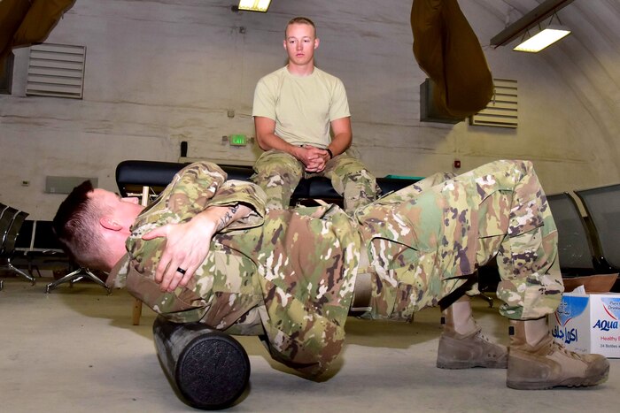 An airman does situps while another airman watches.