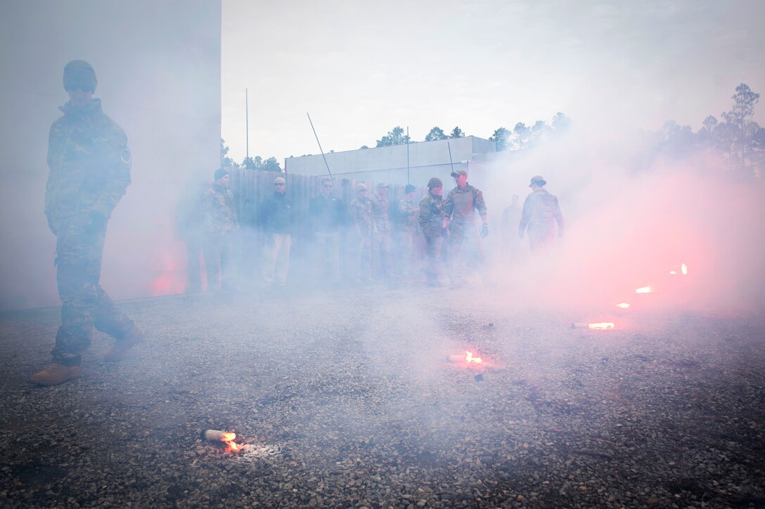 An Air Force instructor, center, ensures airmen properly ignite their smoke flares.