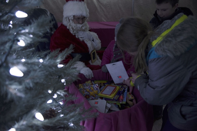 Children look through Santa's toy sack for a toy to keep Dec. 8, 2017, at Mountain Home Air Force Base, Idaho. After Gunfighter Glow families and children were able to talk to Santa and tell them what they wanted for Christmas. (U.S. Air Force photo by Senior Airman Lauren-Taylor Levin)