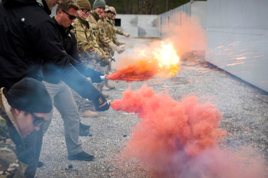 Air Force airmen light smoke flares while participating in combat survival training.