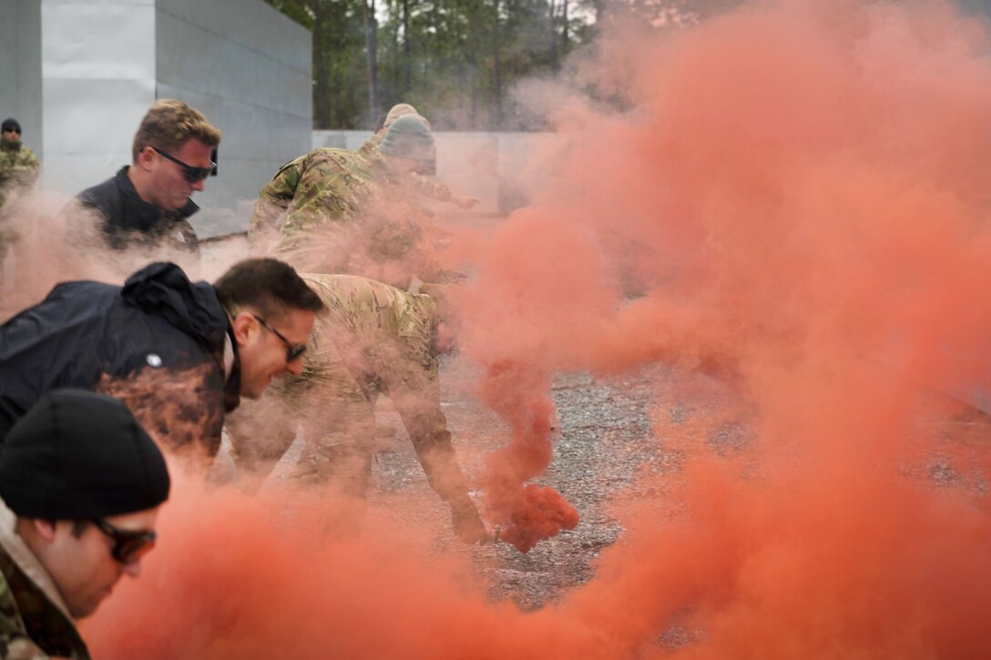 Air Force airmen lite red smoke flares while participating in combat survival training.