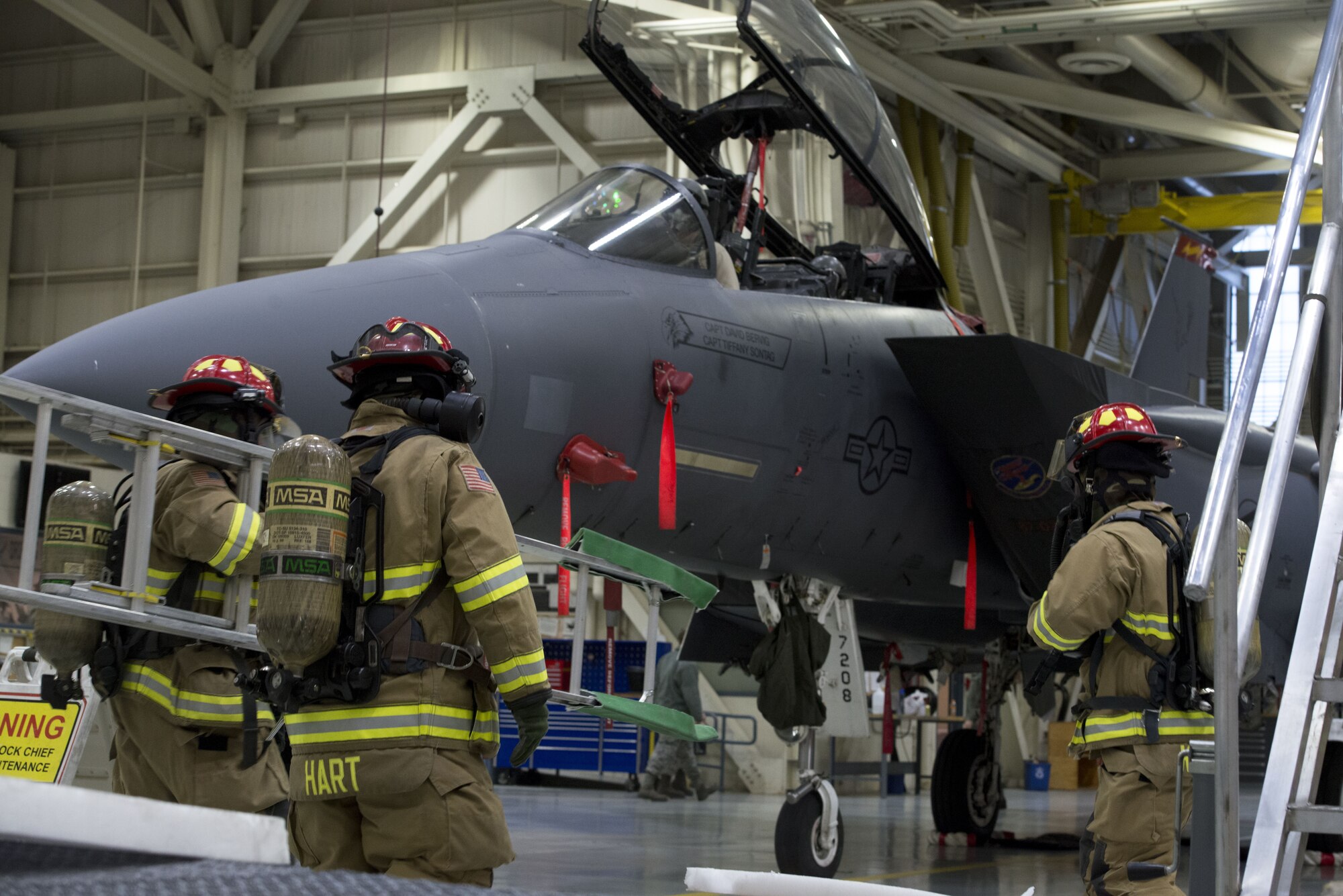Photograph of Airmen from the 366th Civil Engineer Squadron carry a ladder to an F-15E Strike Eagle Dec. 5, 2017, at Mountain Home Air Force Base, Idaho. The base participated in a week-long exercise to train for potential real world contingencies. (U.S. Air Force Photo by Airman 1st Class JaNae Capuno)
