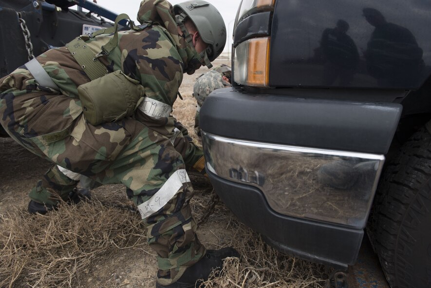 Photograph of Senior Airman Jeffrey Robison, 366th Logistics Readiness Squadron vehicle operator, places a chain on a simulated damaged vehicle Dec. 6, 2017, at Mountain Home Air Force Base, Idaho. Before any vehicle can be towed it must have a two part secure system or else the vehicle can not be lifted. (U.S Air Force photo by Senior Airman Lauren-Taylor Levin)