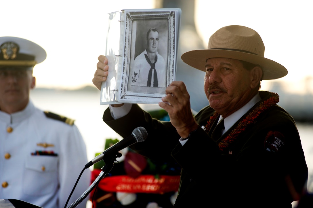 A member of the Park Service holds a black and white photograph.