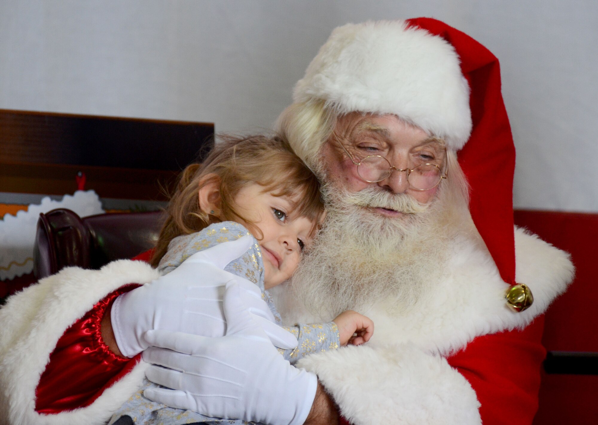 Santa hugs a child after she tells him her holiday wishes at Dobbins Air Reserve Base, Ga. Dec. 3, 2017. Sitting on a stage in a hangar usually reserved for commander’s calls and aircraft maintenance, children lined up for what seemed like miles to ask the Clauses for everything from bicycles to video games. (U.S. Air Force photo by Don Peek)