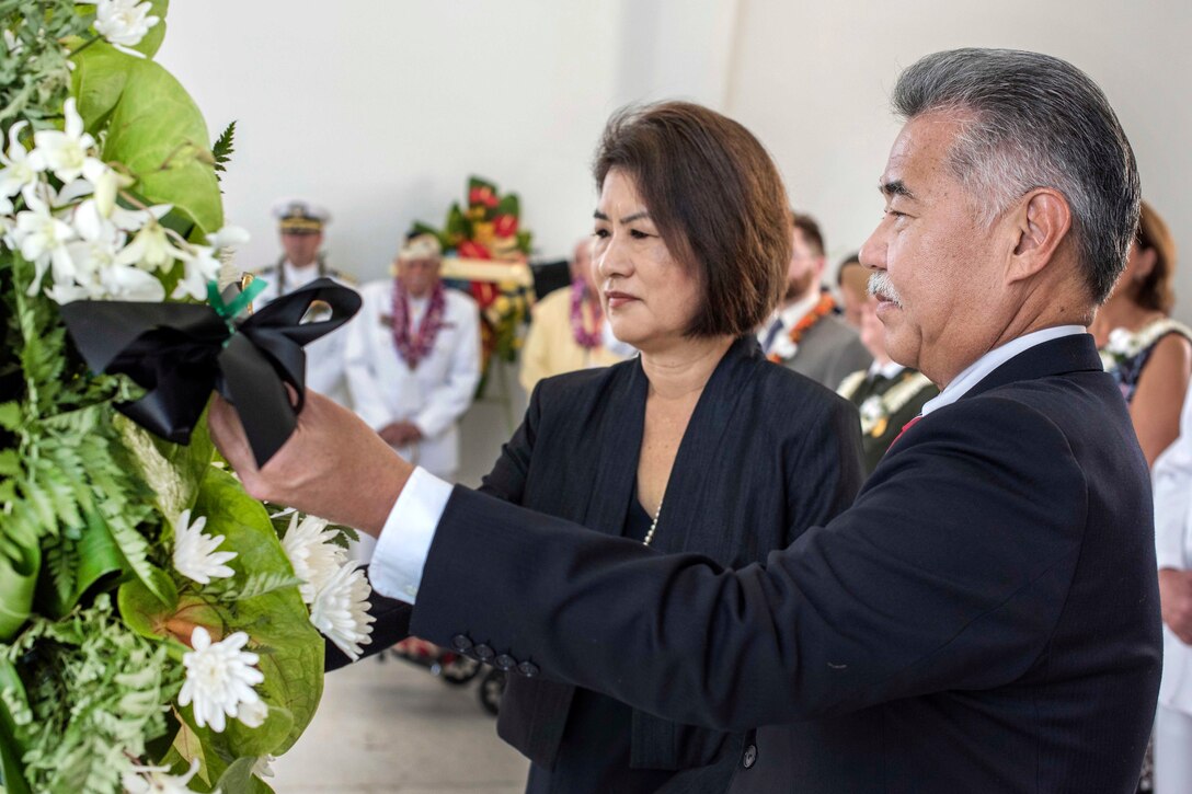 Two people place a wreath.