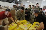 U.S. Air Force Lt. Col. Melvin Ibaretta, the deputy commander of the Air Force Reserve’s 624th Regional Support Group, works with members of the 44th Aerial Port Squadron by grabbing a bag of rice to include in a Christmas bundle during Operation Christmas Drop Dec. 9, 2017, at Andersen Air Force Base, Guam. Operation Christmas Drop has been providing critical supplies to 56 Micronesian Islands since 1952. The 44th Aerial Port Squadron supports the 624th Regional Support Group’s mission of providing combat readiness, quality management and peacetime deployments in the Pacific area of responsibility. (U.S. Air Force photo by Master Sgt. Theanne Herrmann)