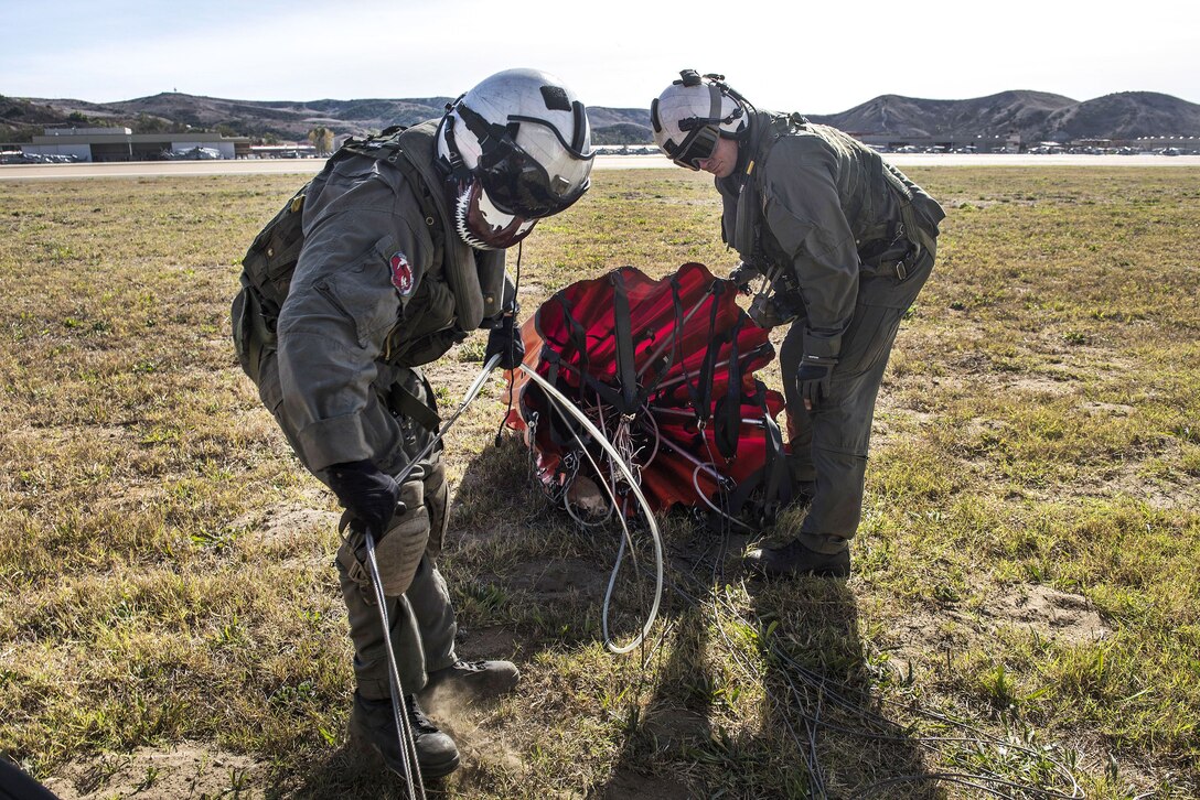 Two service members straighten out ropes to connect to a bucket firefighting system.