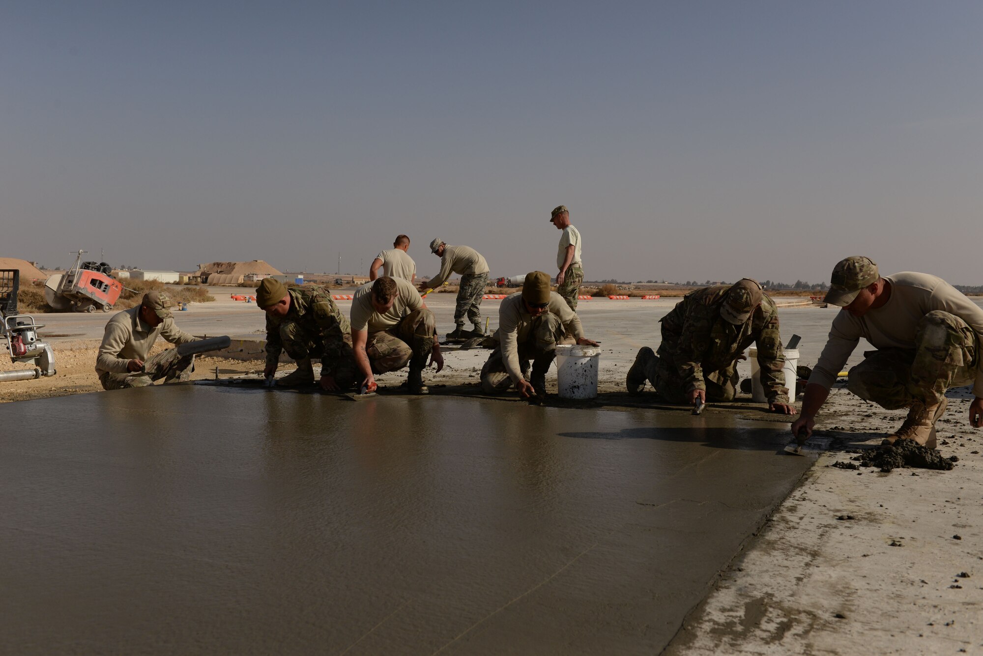 Airmen assigned to the 332nd Expeditionary Civil Engineer Squadron smooth out the edges of a concrete slab before covering it with burlap and tarp so that it will dry correctly without debris at an undisclosed location in Southwest Asia Nov. 28, 2017. During the last two weeks, Air National Guardsmen and active duty personnel, laid 1,000 yards of concrete, repaired 60 slabs and 425 spalls in order to keep the flight line ready for U.S. and Coalition forces flying sorties. (U.S. Air Force photo by Senior Master Sgt. Cohen A. Young)