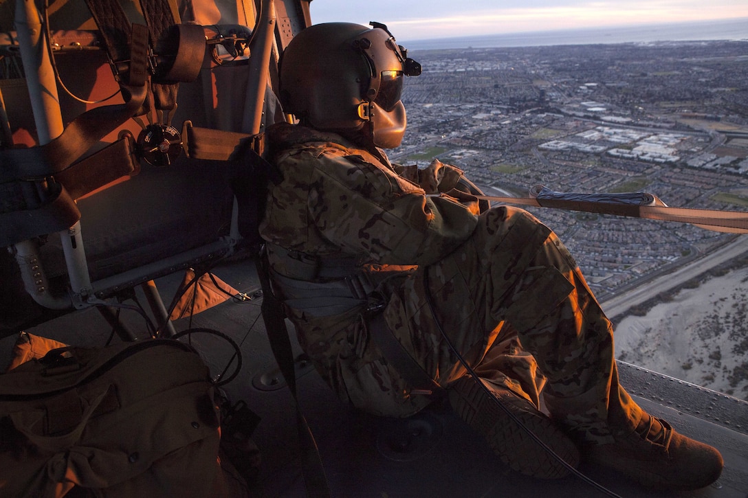 A soldier looks out from a helicopter.