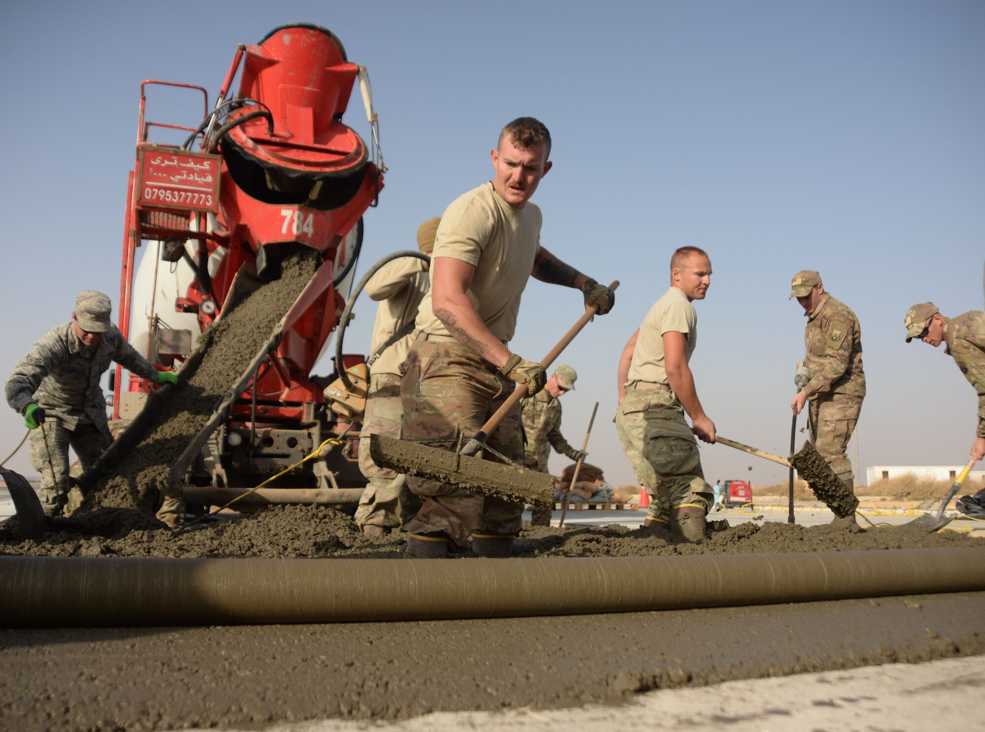 Airmen from six civil engineering job specialties, assigned to the 332nd Expeditionary Civil Engineer Squadron, work together to pour, flatten and edge a new concrete slab on a runway at an undisclosed location in Southwest Asia Nov. 28, 2017.