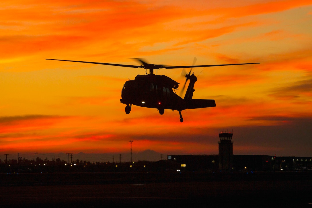 A helicopter takes off against an orange sky.