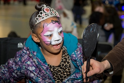 Jailynn Mercer, Parents and Children Fighting Cancer holiday party attendee, looks at her reflection after having her face painted on Joint Base Andrews, Md., Dec. 9, 2017. Face painting, a puppet show and dance performances were some of the many activities children were able to enjoy.