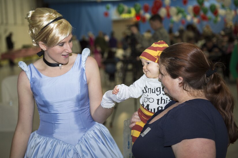 Cinderella greets Tiffany and Samuel Barnett, Parents and Children Fighting Cancer holiday party attendees, during the event’s 30th anniversary on Joint Base Andrews, Md., Dec. 9, 2017. Volunteers dressed up as popular characters and interacted with visitors. Hangar 3 was turned into a winter wonderland to allow military families whose lives have been affected by cancer to gather together and enjoy the free celebration.