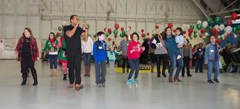 30th Annual Parents and Children Fighting Cancer holiday party attendees dance during the festive celebration in Hangar 3 on Joint Base Andrews, Md., Dec. 9, 2017. During performance breaks, guests were able to dance to various songs throughout the event.