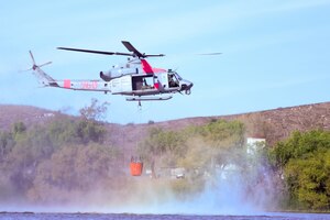 A helicopter hovers over water.