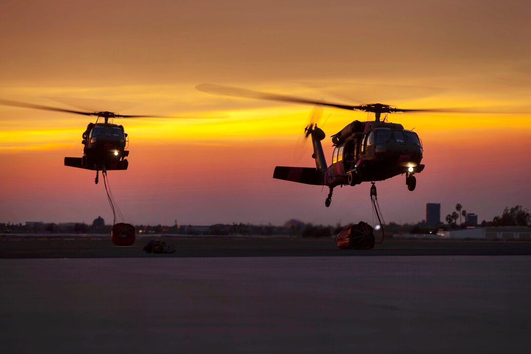 Two California Army National Guard UH-60 Black Hawk helicopters prepare to land at sunset