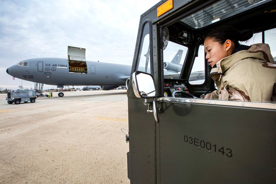 Airman Vince Tsang checks the rear view mirror of a K-loader while in mission oriented protective posture level two gear.