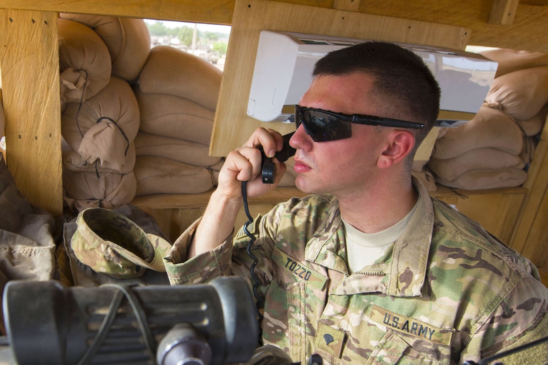 A soldier speaks into a radio microphone