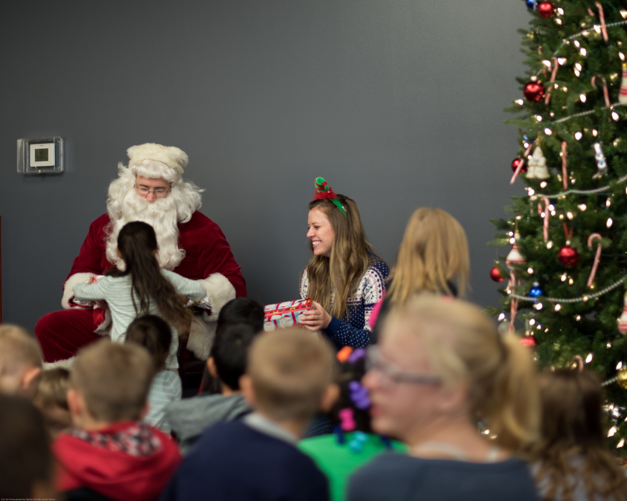 Santa passes out gifts to children at a holiday party sponsored by the Reconnaissance Crew's Booster Club in Dec. 9, 2017, in Bellevue, Nebraska. This was the 44th annual party the RCBC has put on. The event serves as a way for the service members of Offutt Air Force Base to give back to the local community. (U.S. Air Force photo by Senior Airman Jacob Skovo)