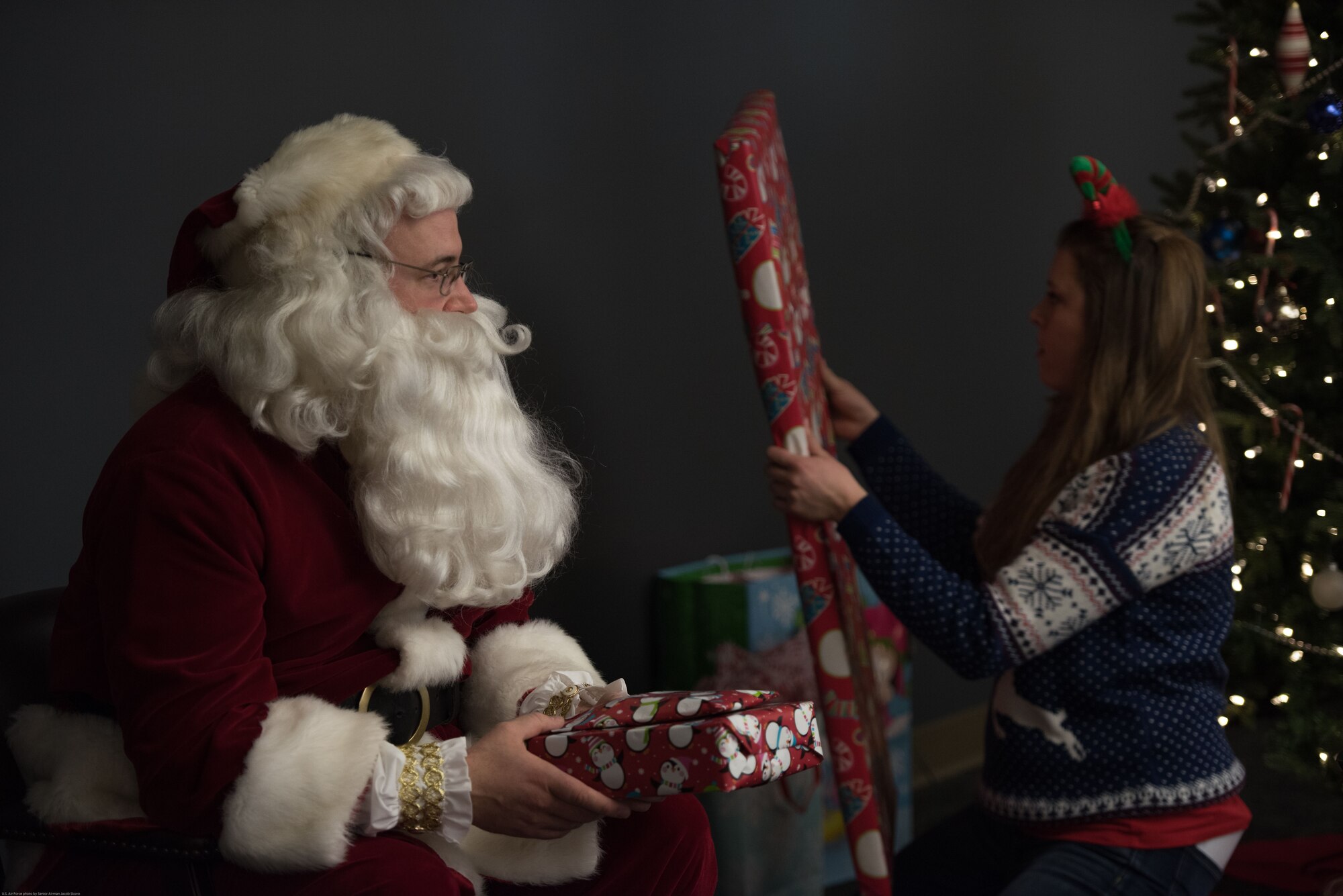 Santa and U.S. Air Force Captain Mary, 343rd Reconnaissance Squadron, passes out gifts to children at a holiday party sponsored by the Reconnaissance Crew's Booster Club in Dec. 9, 2017, in Bellevue, Nebraska. 91 children participated in the 44th annual RCBC holiday party. (U.S. Air Force photo by Senior Airman Jacob Skovo)