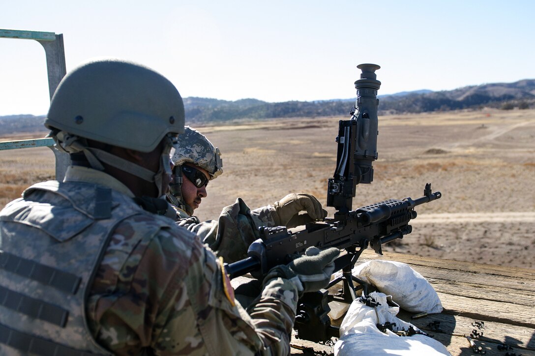 Army Reserve Pfc. Ricardo Ramirez, left, loads a round into an M240B machine gun.