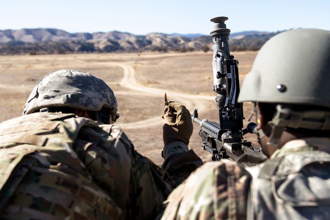 Army Reserve Pfc. Ricardo Ramirez, left, prepares to load a round into an M240B machine gun.