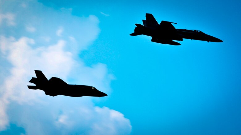 An F-35B Lightning II Joint Strike Fighter and an F/A-18C Hornet fly over-head during the playing of the Marine Corps Hymn during a Relinquishment of Command Ceremony aboard Marine Corps Air Station Beaufort, Sept. 22. During the ceremony, Lt. Col. Michael P. Brennan relinquished command of “The Flying Leathernecks” and then cased the squadron colors for transport. The squadron will stand up aboard Marine Corps Air Station Yuma, Ariz. as an F-35B Lightning II Joint Strike Fighter squadron.