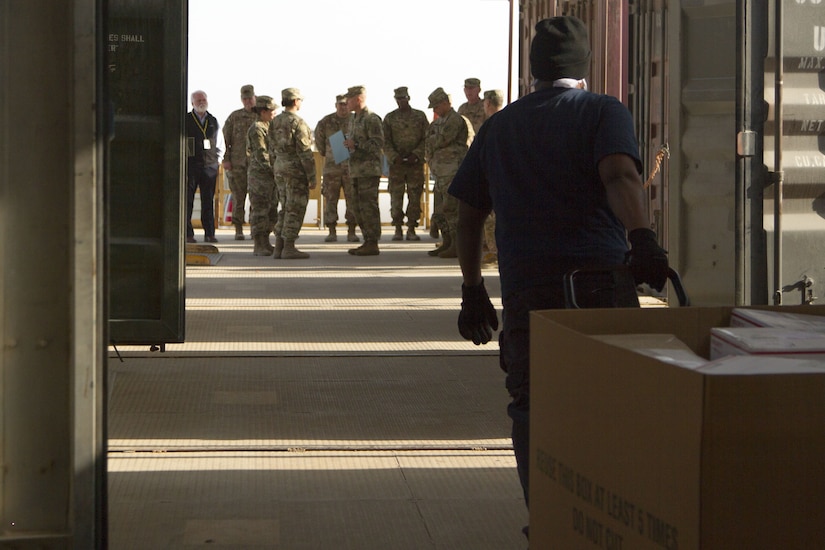 Soldiers standing outside warehouse.