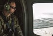 Soldier looks out window of a helicopter.