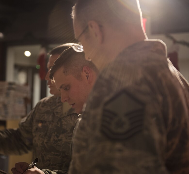 PETERSON AIR FORCE BASE, Colo. — The judges of the gingerbread competition gather around to tally up the scores and review their decisions at the Eclipse Cyber Café on Peterson Air Force Base, Colorado, December 6, 2017. Events like these give leadership a chance to come out and get to know their Airmen. (U.S. Air Force photo by Airman First Class Alexis Christian)