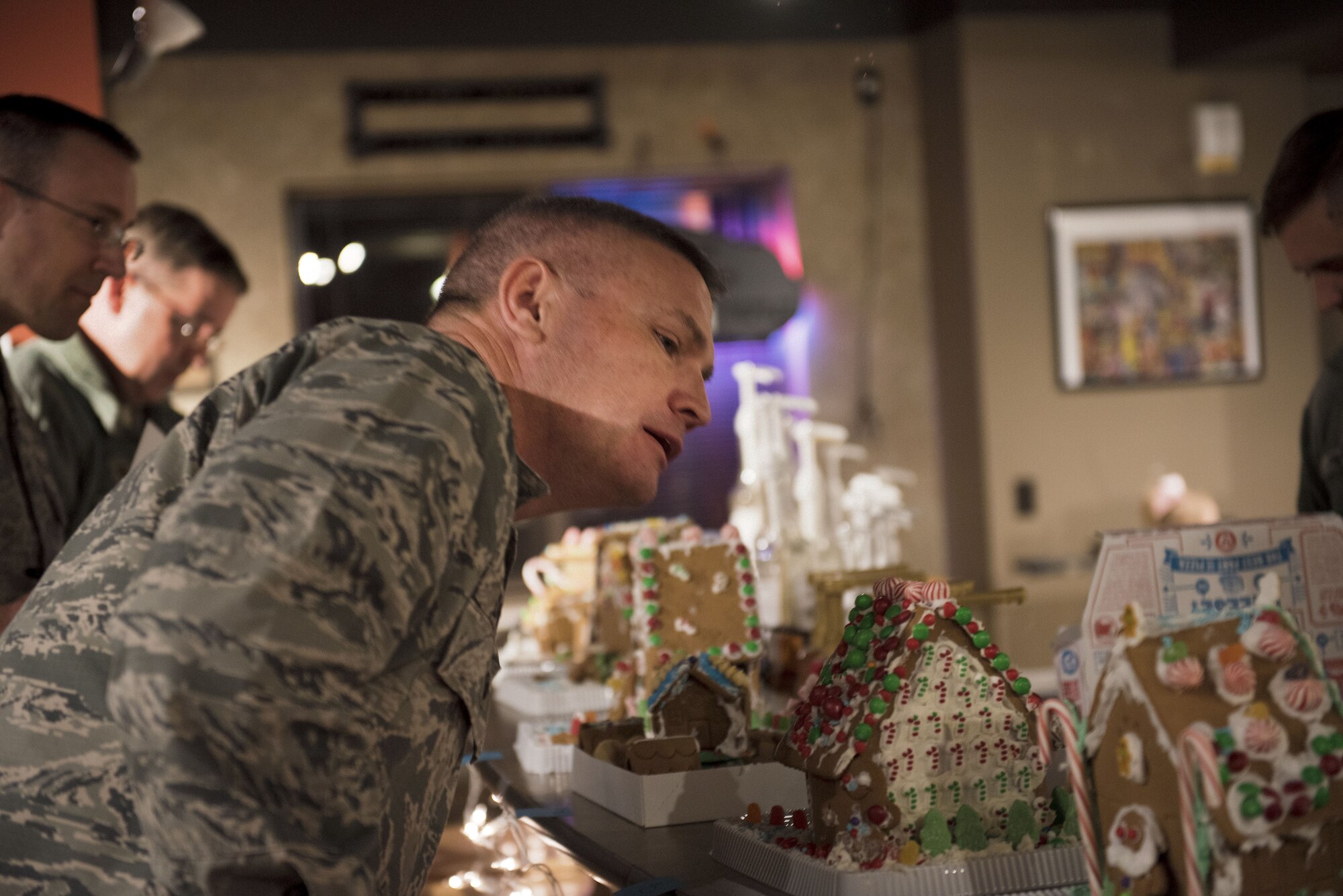 PETERSON AIR FORCE BASE, Colo. — Col. Eric Dorminey, 21st Space Wing vice commander closely inspects one of the entries in the gingerbread competition at the Eclipse Cyber Café on Peterson Air Force Base, Colorado, December 6, 2017. Entries had a wide variety of gingerbread creations including houses, villages, trains, and planes. (U.S. Air Force photo by Airman First Class Alexis Christian)