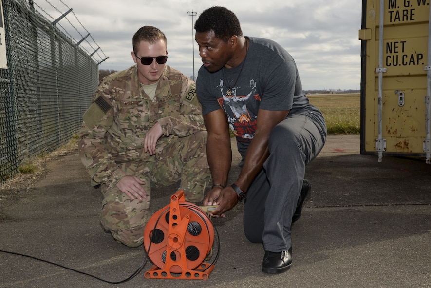 Senior Airman Joel Miller, 436th Civil Engineer Squadron explosive ordnance disposal technician, watches as Herschel Walker detonates a stick of C-4 Plastic Explosives Dec. 5, 2017, at the EOD range on Dover Air Force Base, Del. Walker visited Airmen from several units to see what they do and speak with them about the importance of mental health. (U.S. Air Force photo by Staff Sgt. Aaron J. Jenne)