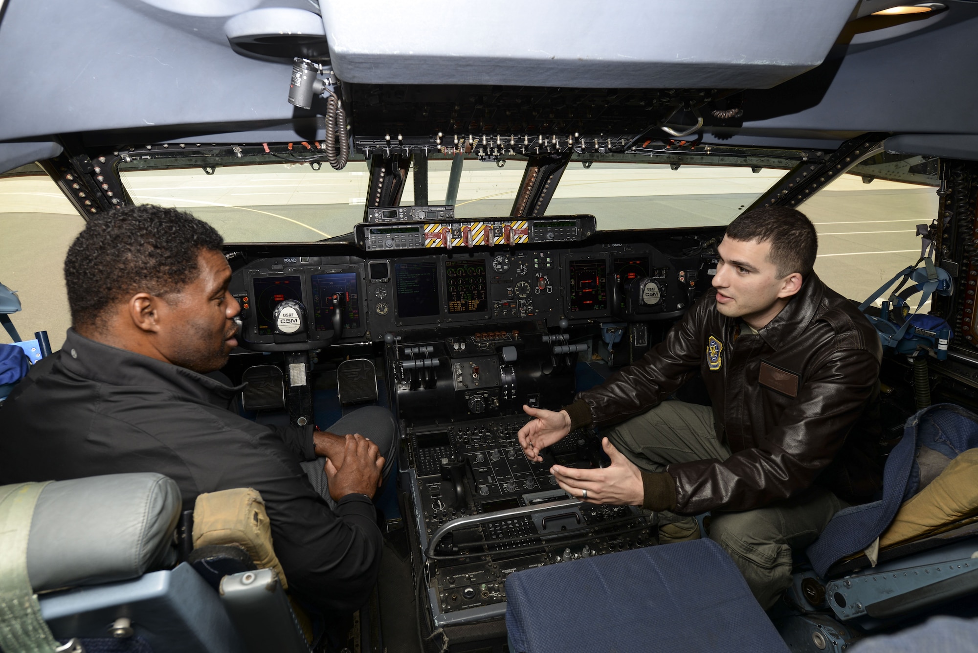 Capt. Eric Wilde II, 9th Airlift Squadron standardization evaluation liaison officer, describes the operation of a C-5M Super Galaxy to professional athlete, Herschel Walker, during a tour Dec. 6, 2017, at Dover Air Force Base, Del. Subject matter experts explained key aspects of Dover AFB operations to Walker, who shared personal stories of overcoming physical and mental hardships throughout his life. (U.S. Air Force photo by Staff Sgt. Aaron J. Jenne)