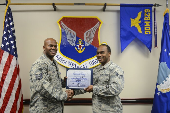 Senior Airman Ramel Hicks, right, 628th Medical Group health services manager and command support staff administrator, receives the Diamond Sharp Award certificate from Tech. Sgt. Robert Niter, left, 628th MDG interim first sergeant, in the 628th MDG conference room at Joint Base Charleston, S.C., Dec. 12, 2017.