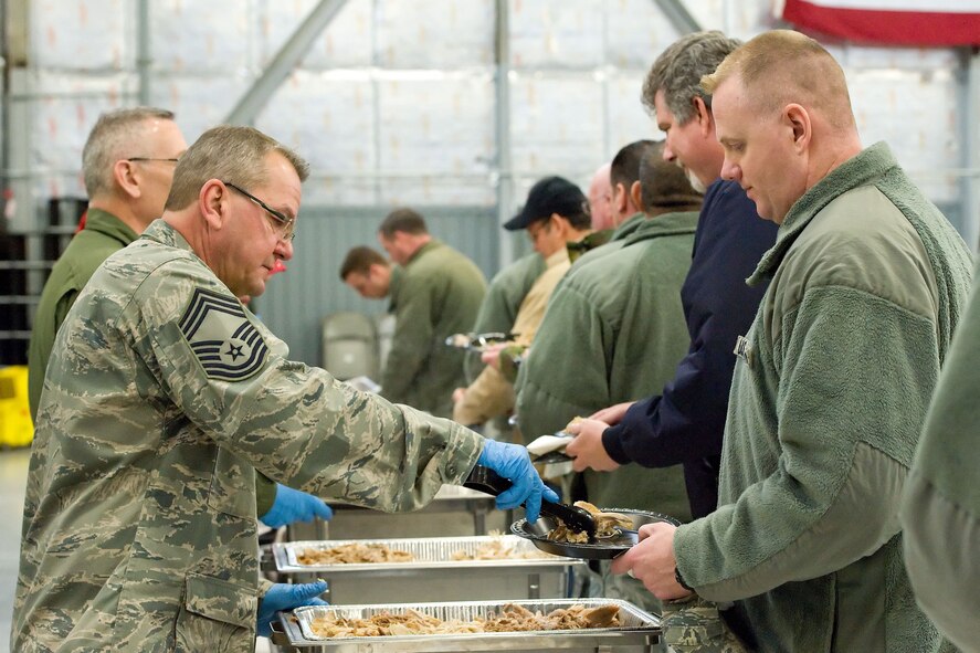Chief Master Sgt. James Dowd, 512th Aircraft Maintenance Squadron, serves a Team Dover member during the 11th Annual Feed the Troops day shift dinner Dec. 23, 2014, in Hangar 792 on Dover Air Force Base, Del. Thirty-eight turkeys were cooked at the Dover Downs kitchen and transported to the base for day and night shift meal sittings. (U.S. Air Force photo by Roland Balik)