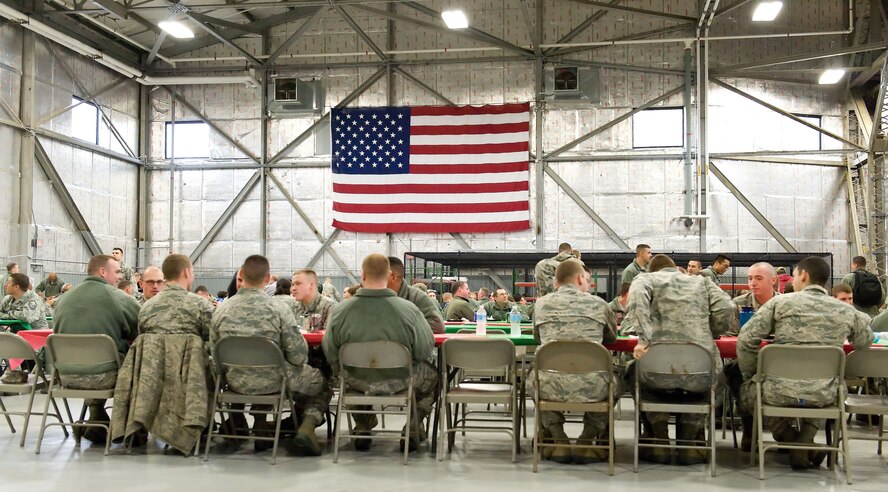 Some of the 450 Team Dover members relax and share a meal during the 11th Annual Feed the Troops day shift dinner Dec. 23, 2014, in Hangar 792 on Dover Air Force Base, Del. Approximately 575 meals total were served to Team Dover members during the day and night shift meal sittings. (U.S. Air Force photo by Roland Balik)