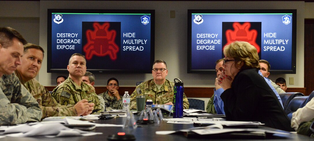 People sitting at a conference room table observing a PowerPoint presentation.