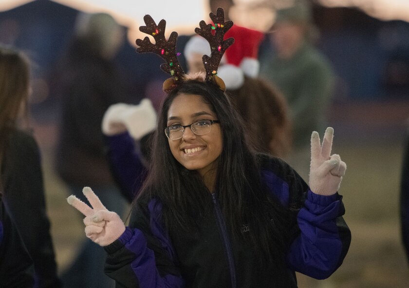 A Clovis High School Dance Team member flashes the peace sign during the holiday parade and tree lighting ceremony Dec. 7, 2017, at Cannon Air Force Base, New Mexico. The dance team and the Clovis High School Marching Band led the parade through base housing, finishing at the Landing Zone. (U.S. Air Force Base photo by Staff Sgt. Michael Washburn/Released)