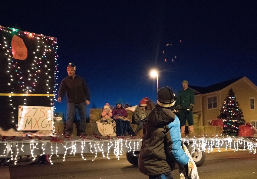 Candy flies through the air toward awaiting children during the holiday parade and tree lighting ceremony Dec. 7, 2017, at Cannon Air Force Base, New Mexico. The parade included floats decorated by the squadrons and an appearance by Santa Claus himself. (U.S. Air Force photo by Staff Sgt. Michael Washburn/Released)