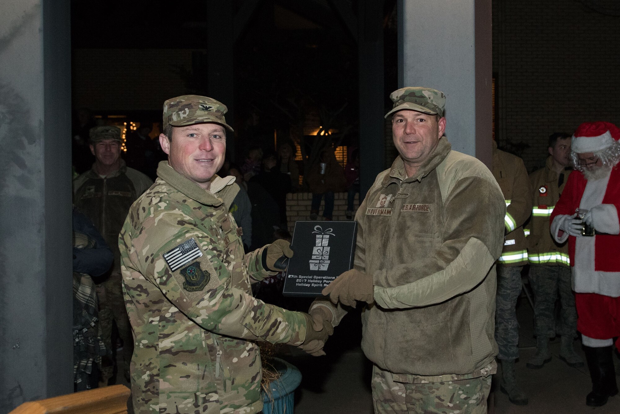 Col. Michael Conley, 27th Special Operations Wing vice commander, presents a member of the 27th Special Operations Maintenance Group an award for most spirited float during the holiday parade and tree lighting ceremony Dec. 7, 2017, at Cannon Air Force Base, New Mexico. Conley handed out awards for best light display, most spirited float and best overall float. (U.S. Air Force photo by Staff Sgt. Michael Washburn/Released)