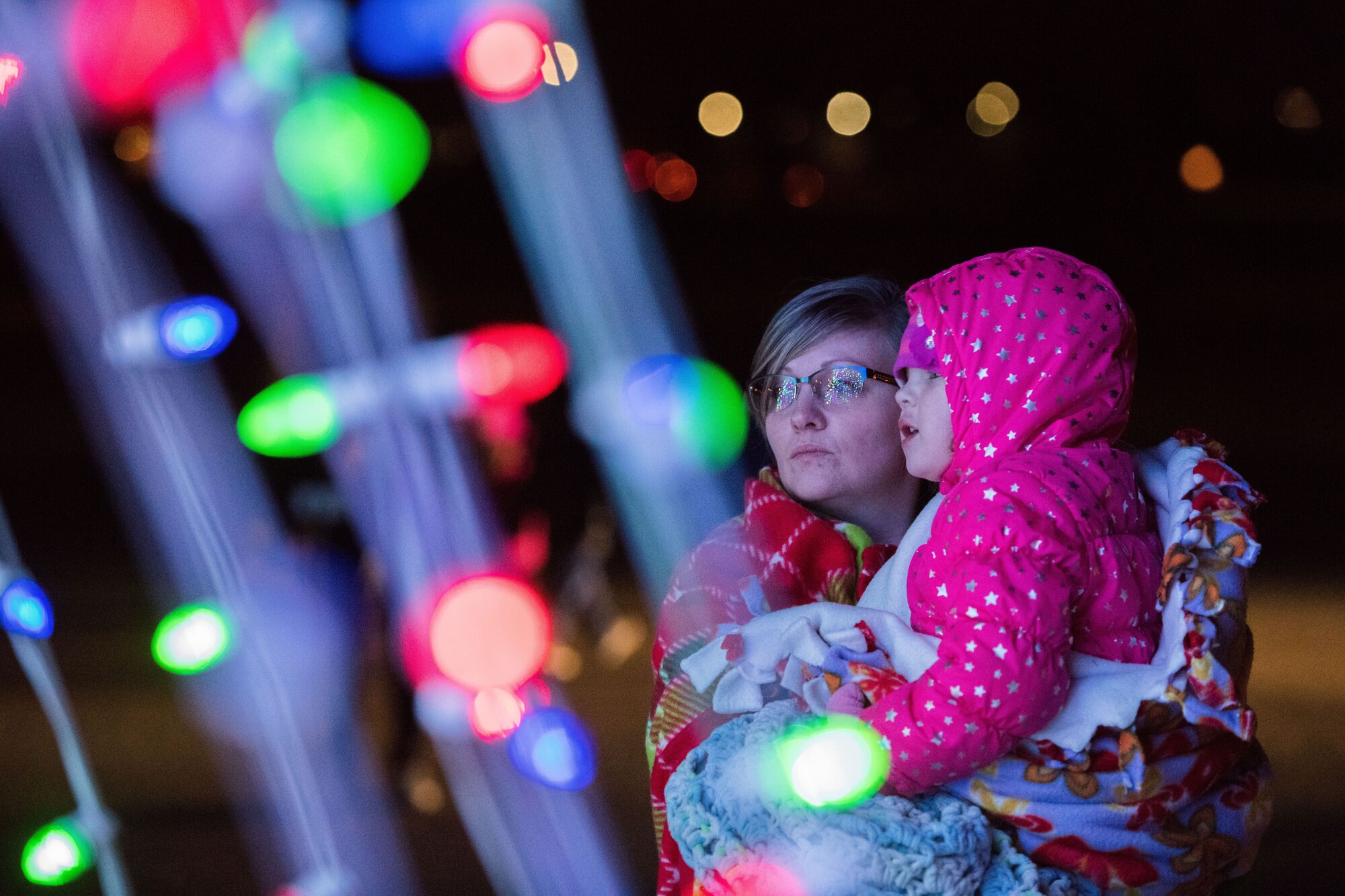 A mother and child look at the holiday lights outside of the Landing Zone during the holiday parade and tree lighting ceremony Dec. 7, 2017, at Cannon Air Force Base, New Mexico. The parade included floats decorated by the squadrons and an appearance by Santa Claus himself. (U.S. Air Force photo by Staff Sgt. Michael Washburn/Released)