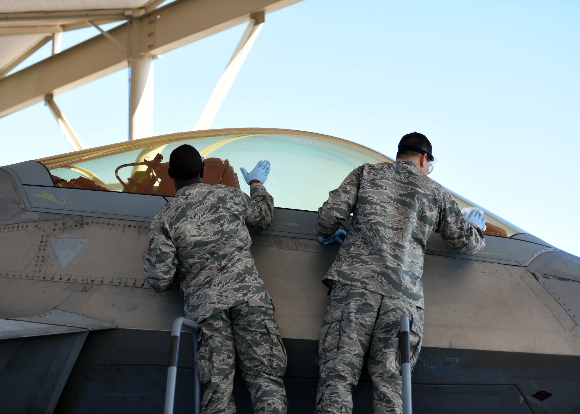 U.S. Air Force Senior Airman Gerald Austin (left), 44th Fighter Group, 44th Maintenance Squadron aircraft maintenance journeyman, and Col. Michael Hernandez, 325th Fighter Wing commander (right), clean the canopy of an F-22 Raptor at Tyndall Air Force Base, Fla., Nov. 3, 2017. Austin was selected to be shadowed by the commander for the Airman Shadow Program, a program that allows exceptional Airmen the opportunity to showcase their daily duties while interacting with the base commander. (U.S. Air Force photo by Airman 1st Class Isaiah J. Soliz/Released)