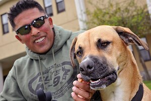 A soldier gives a treat to a dog.
