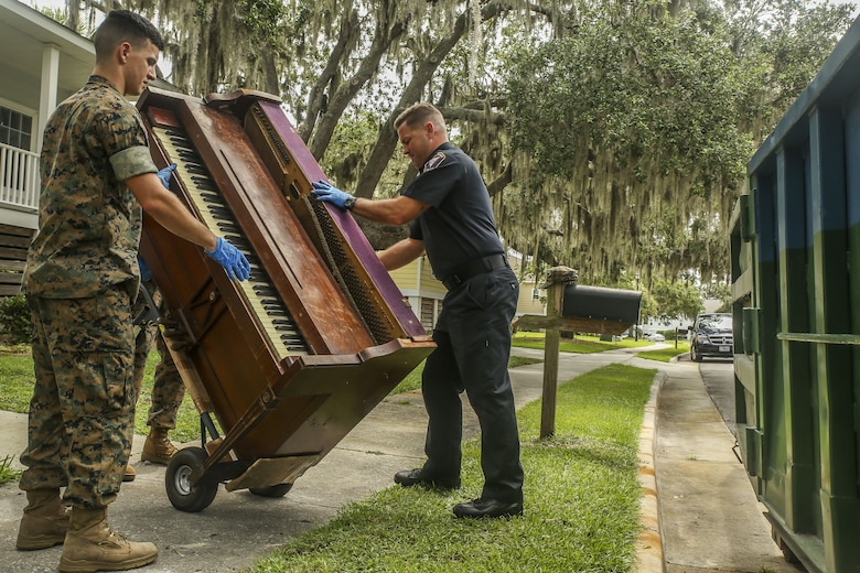 Ron Videtto, right and Lance Corporal Alfonso Quevedo, left prepare a piano on a handcart as part of  a job to help a family affected by a house fire aboard Marine Corps Recruit Depot, July 27.  The Provost Marshals Office volunteered their time to help the family in need as part of their mission to protect and serve. Videtto and Quevedo work aboard  Marine Corps Recruit Depot Parris Island.