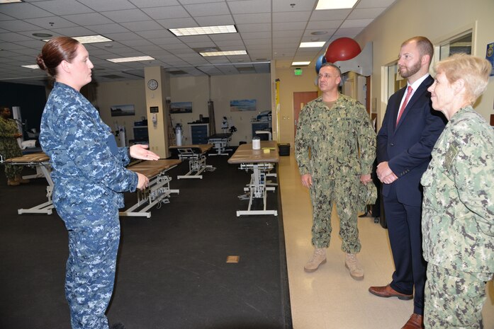 Navy Lt. Elizabeth Plowman, left, physical therapist and head of Naval Health Clinic Charleston's Physical Therapy Department, discusses the many physical therapy services available to service members and Veterans at the joint VA-DoD physical therapy clinic with Daniel Patrick Head, second from right, Lowcountry Regional Director for the Office of Senator Lindsey Graham, as he toured the healthcare facility Dec. 5. During Head's visit to NHCC, he was briefed on NHCC's mission and priorities, its role in supporting the Navy and Joint Base Charleston and its impact on the local community and economy.