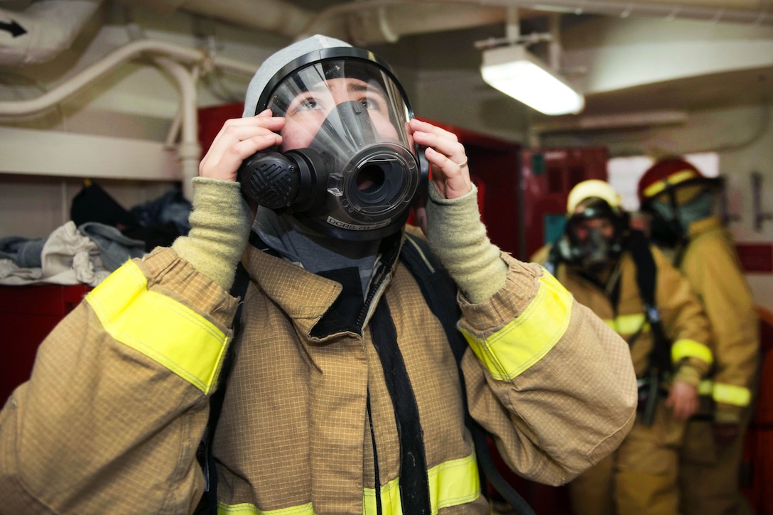 Navy Seaman Alejandra Navarro puts on a self-contained breathing apparatus mask.